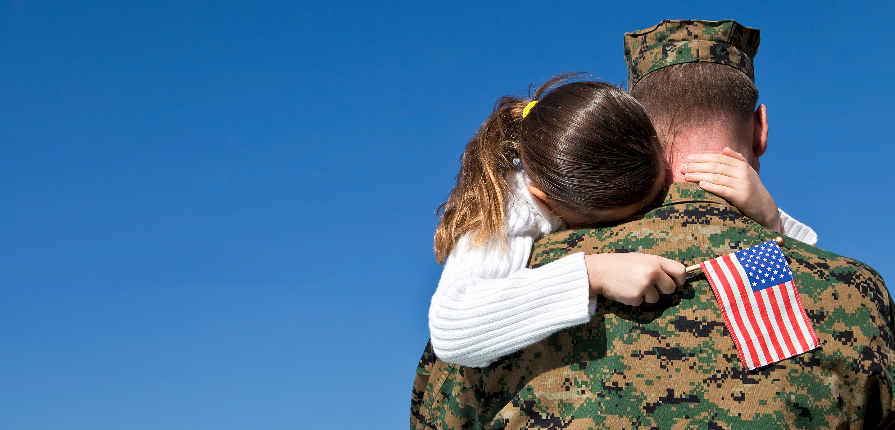 Girl hugging military man with American flag